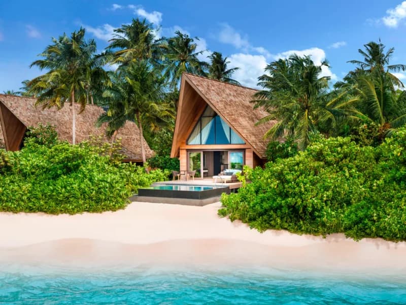 Beachfront villa framed by palm trees at St. Regis Vommuli